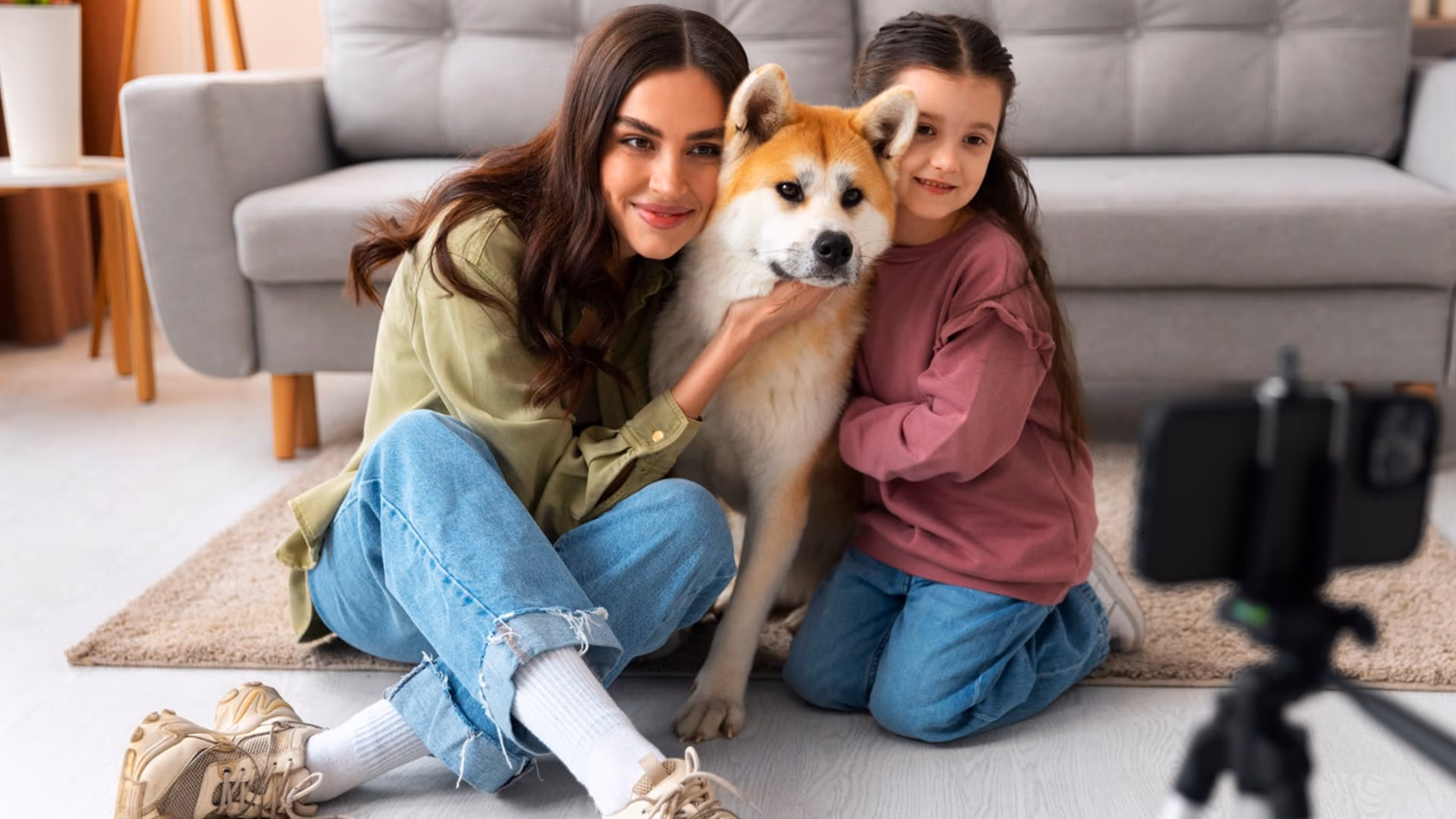 A happy family sitting in a sunny field with their dog posed lovingly in front of them